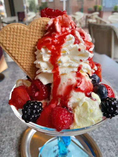 Hoher Eisbecher mit Beeren, Sahne und zwei knusprigen Eiswaffeln