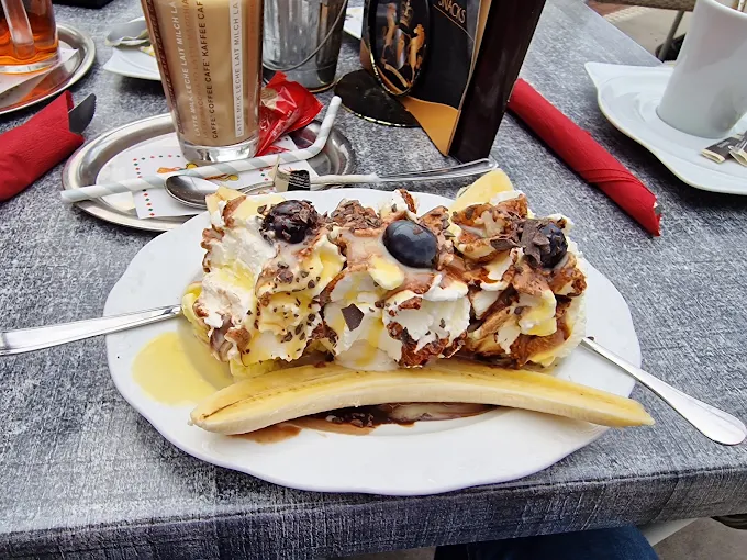 Waffel mit Eis, Sahne und Schokoladensauce auf einem weißen Teller