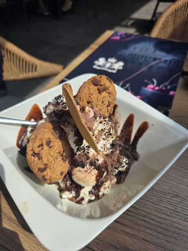 Eisbecher mit Schokoladensauce, Waffelröllchen und Cookies