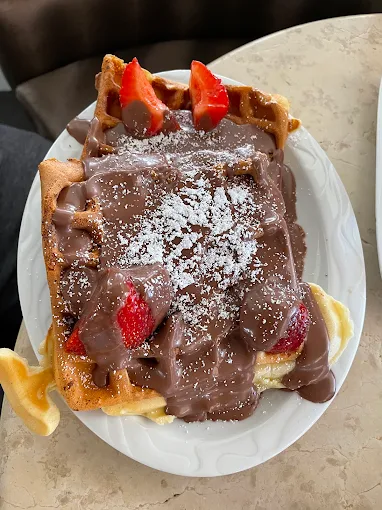 Waffel mit Schokoladensauce, Puderzucker und frischen Erdbeeren