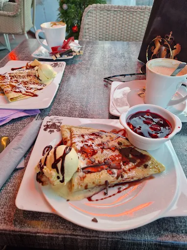 Gedeckter Cafétisch mit süßen Speisen, Beeren und Caffè
