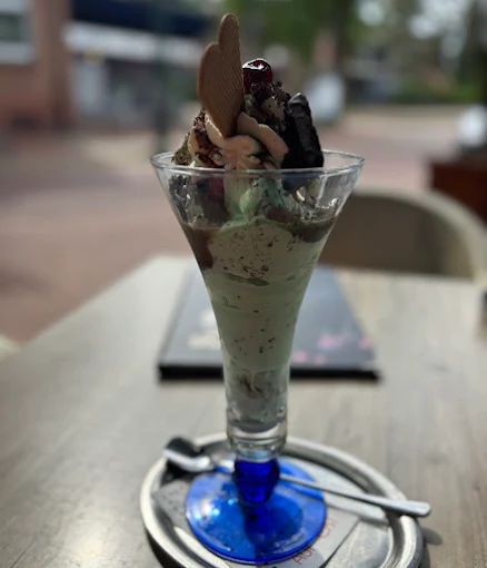 Grüner Eisbecher mit Schokoladensauce in einem blauen Glas
